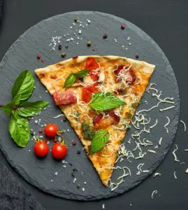 Delicious triangular slice of pizza with smoked sausages, mushrooms, tomatoes