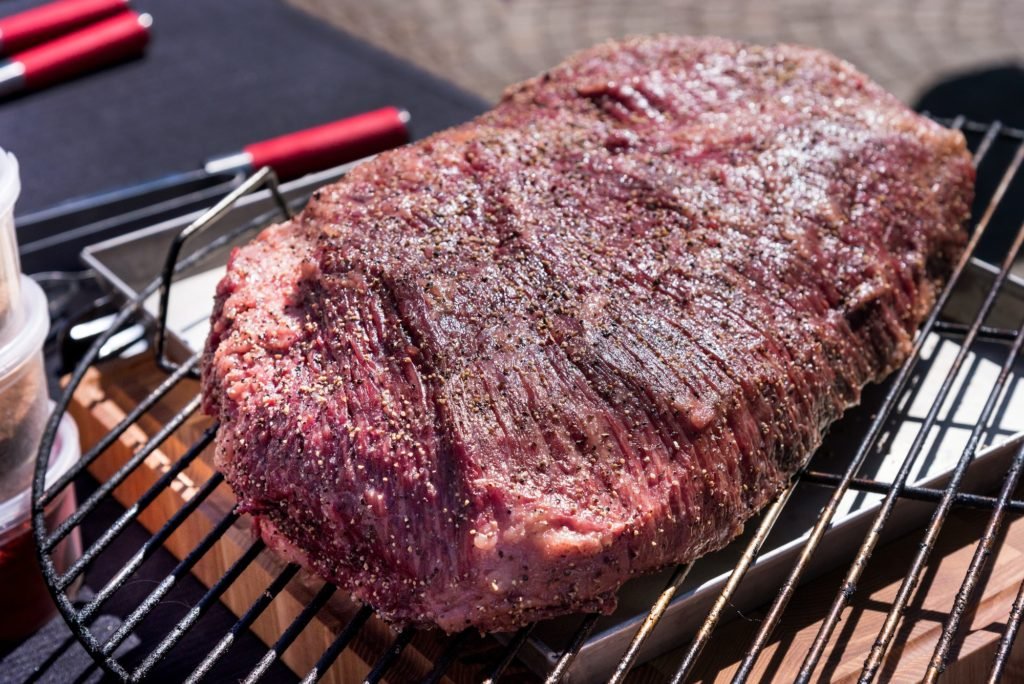 Portion of beef brisket seasoned with spices ready for grilling