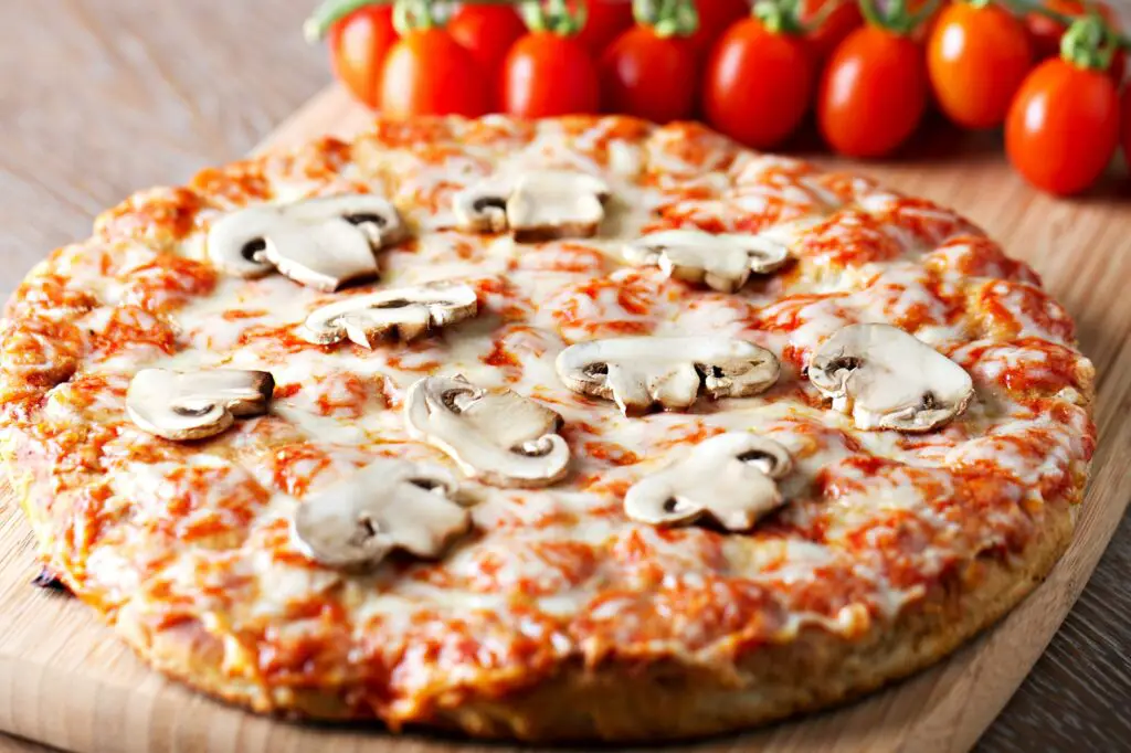 Fresh delicious pizza baked pizza with tomato, mozzarella cheese and mushrooms.