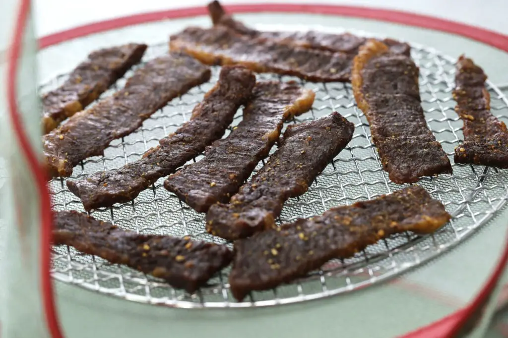 homemade beef jerky, drying marinated meat in the net in the sun.
