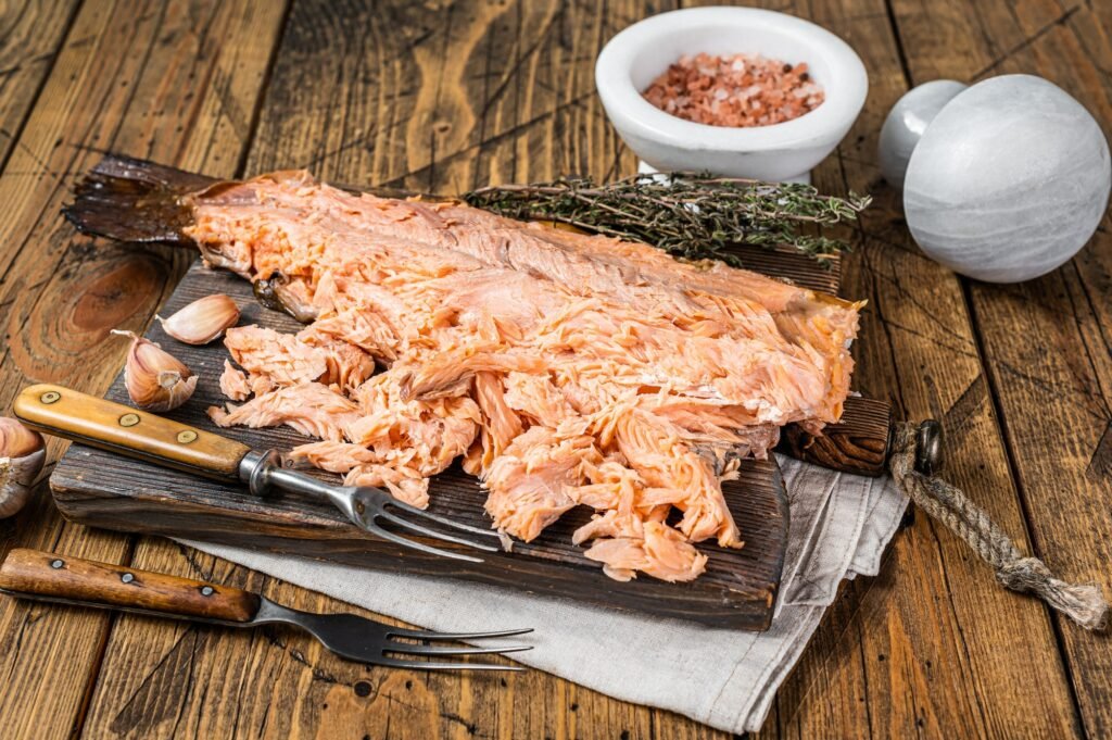 Hot smoked salmon fish fillet on a wooden board. Wooden background. Top view