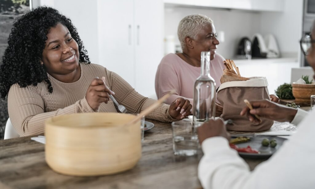 Happy afro Latin family eating healthy lunch with fresh vegetables at home